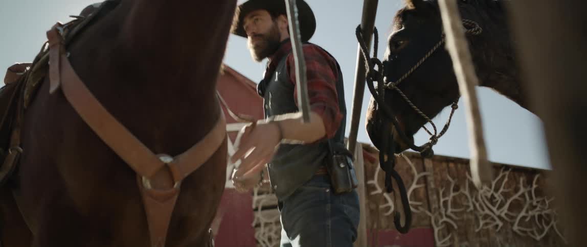 A man outdoors saddling a horse
