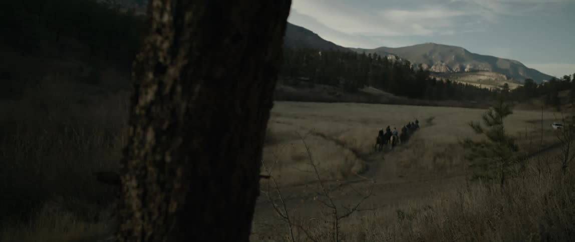 People riding horses on a trail amid mountains and a landscape