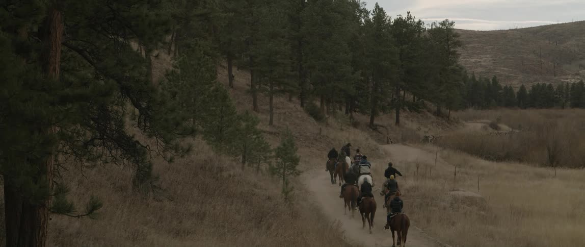 People moving on horses on a path near a mountain at midday