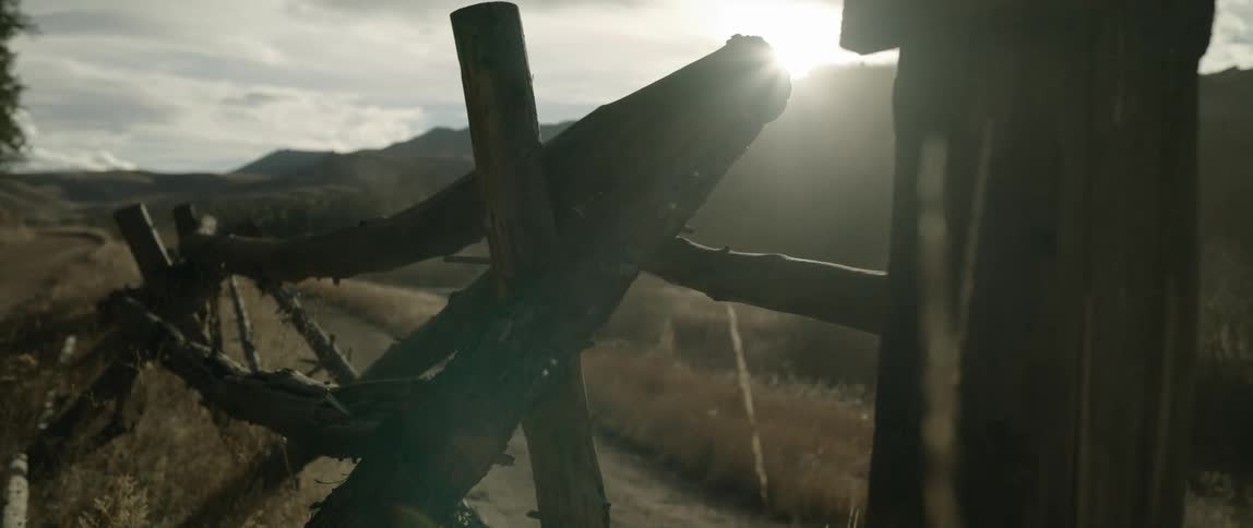 Sunlight shines behind a wooden fence in the countryside