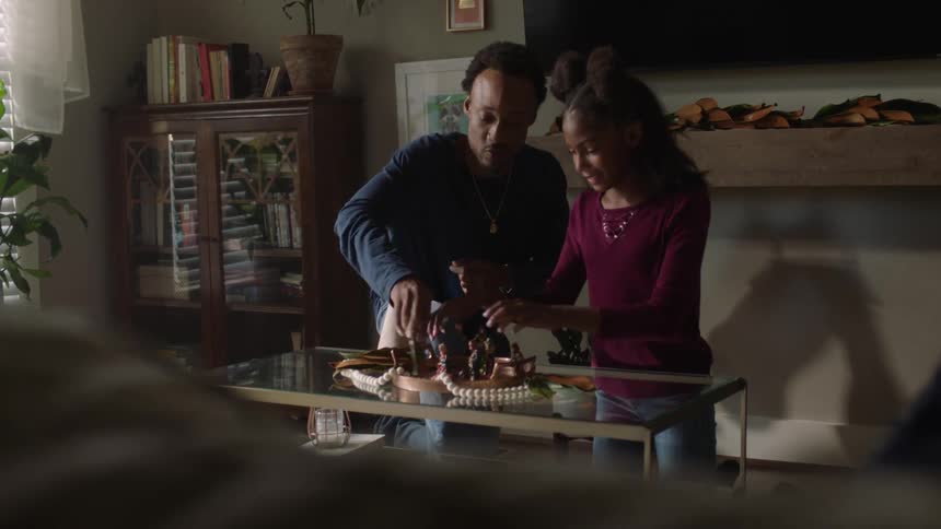 A man and a preteen girl are playing with objects on a glass table