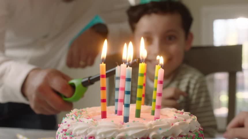 Person lighting the candles on a cake for a smiling child