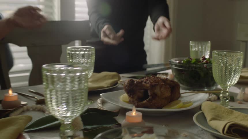 Women placing a roast chicken on a dining table