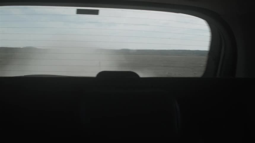 Clouds of dirt fly behind a moving vehicle