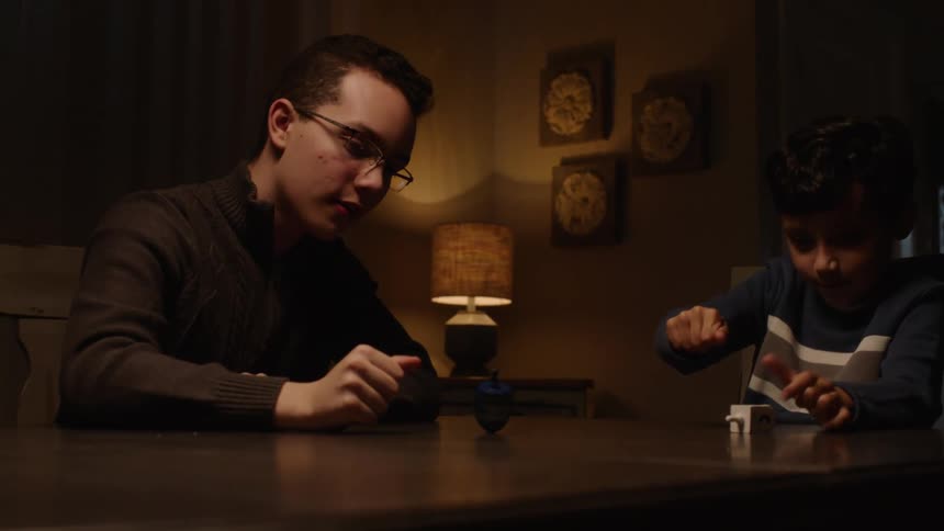 Siblings playing with a toy spinning on the table