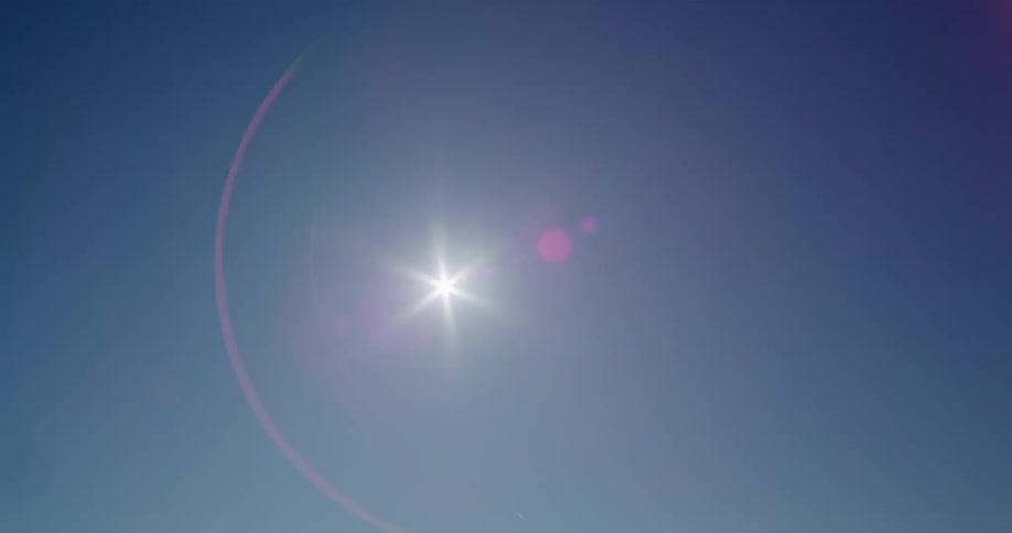 The sun shining brightly in the blue sky