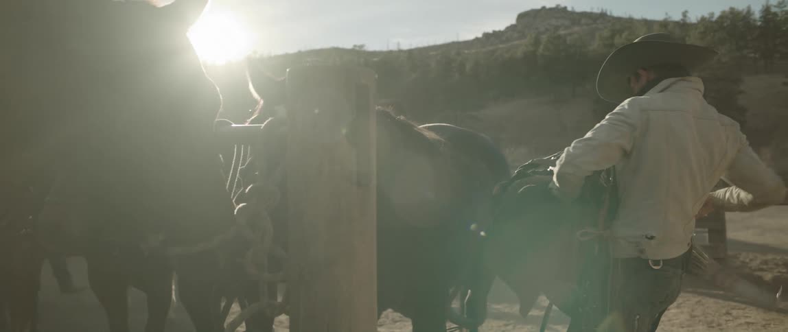 Cowboy takes the saddle out of a horse at morning
