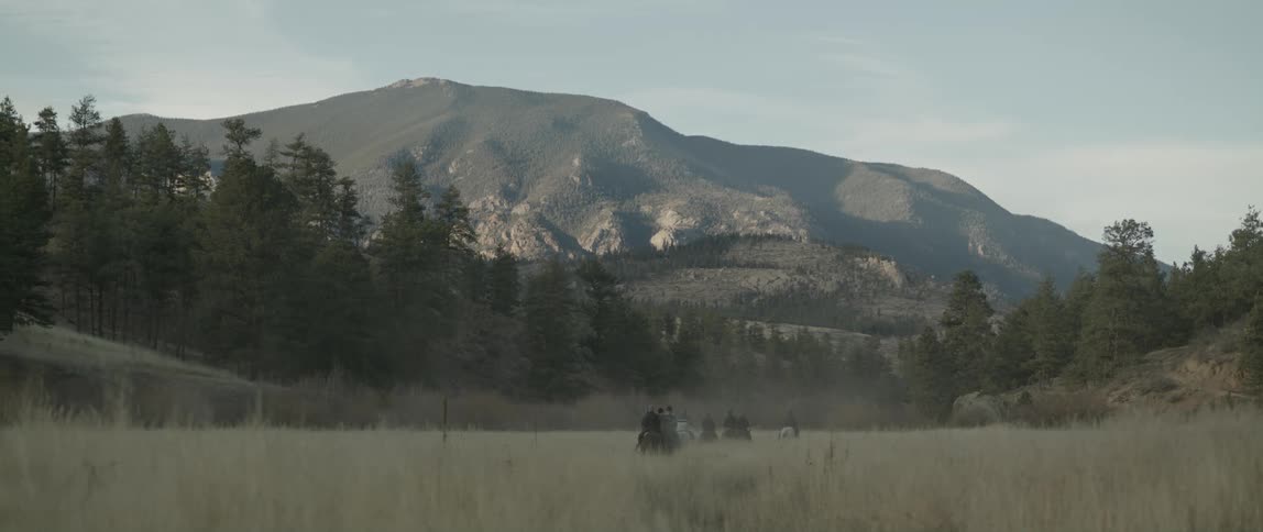 People moving on horses towards a mountain at midday