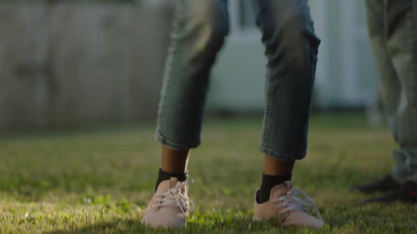 Father helping his daughter jump rope in the backyard
