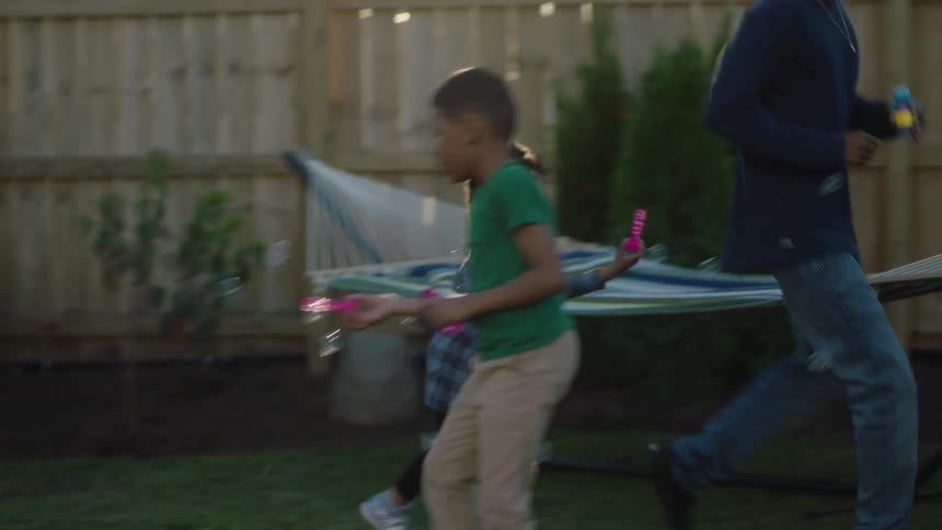 Father running around with his children chasing and playing with soap bubbles