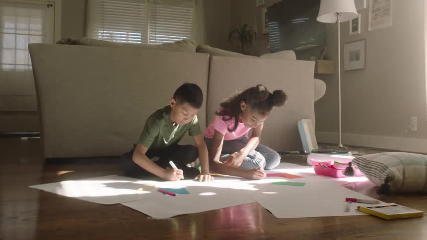 Brothers drawing on sheets of paper on the floor