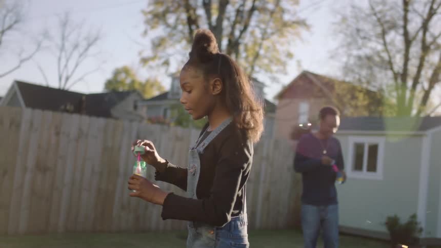 Girl playing with bubbles in the backyard at morning