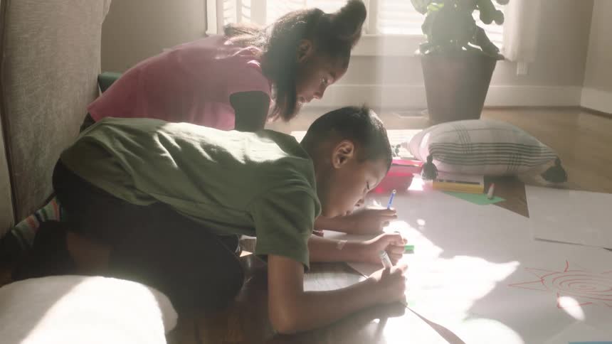 Two sister doing their home work at home on the floor