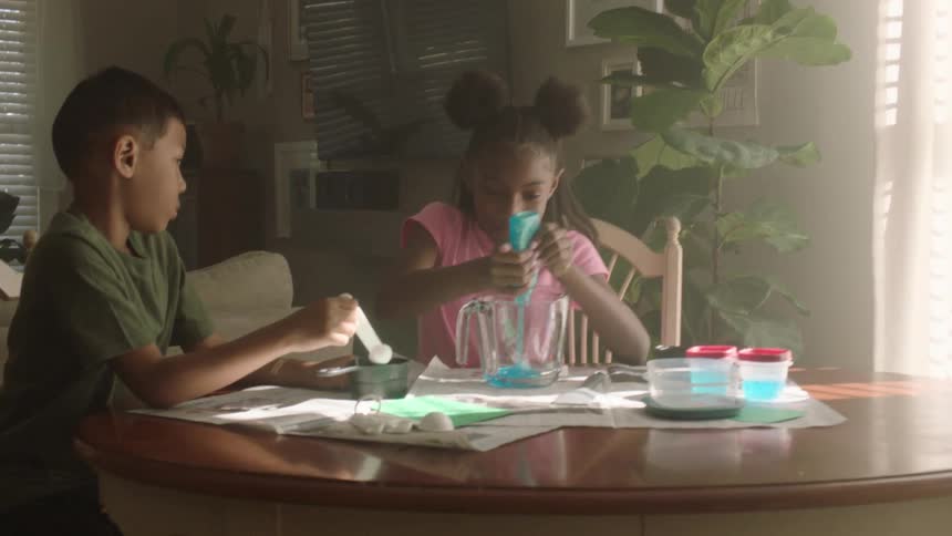 A child is squeezing glue into a pitcher