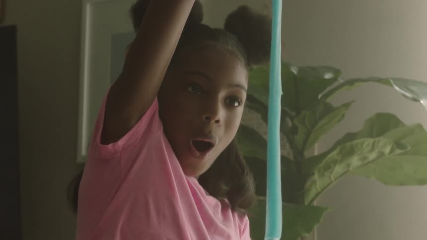 A little girl is amazed as she stretches a blue object that stretches