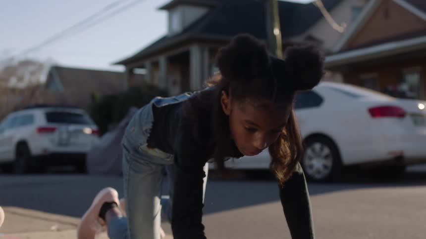 Siblings drawing on the sidewalk of the street with chalk