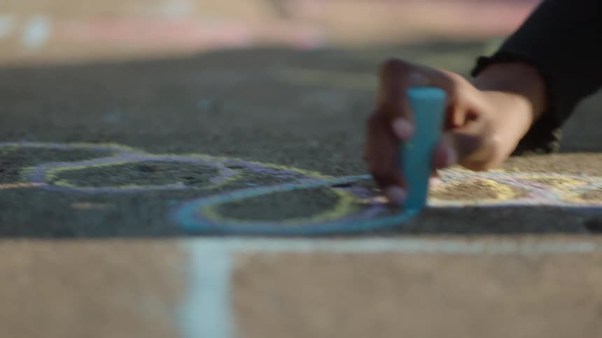 Portrait of a girl drawing with chalk on the sidewalk