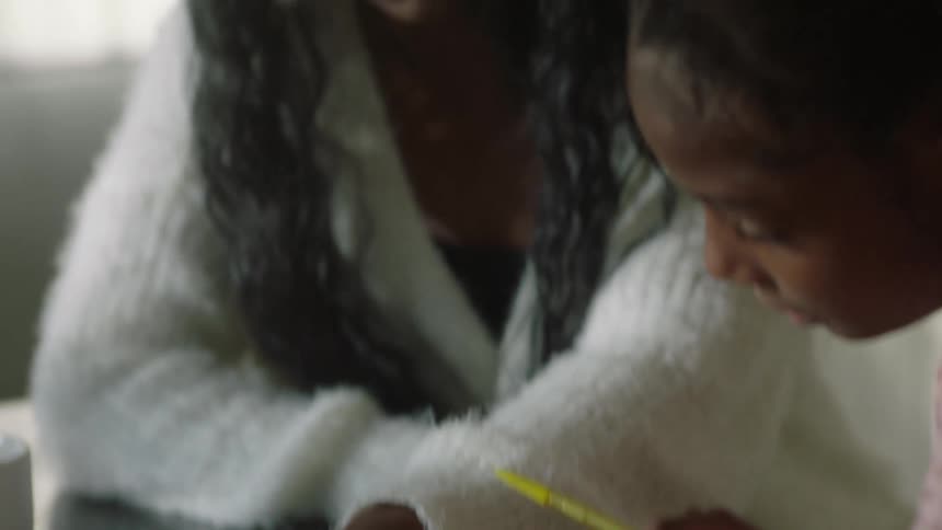 Mother sitting next to her daughter assisting with studies