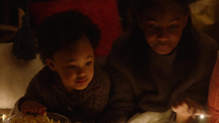 Portrait of a hand reading a book next to her daughter eating popcorn