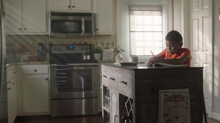 Boy sitting at a countertop in the kitchen writing