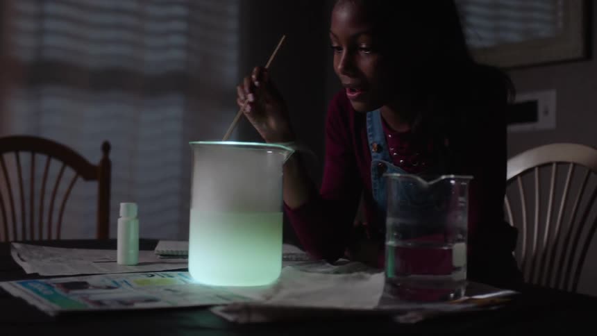 Girl blowing on a chemical container with smoke coming out