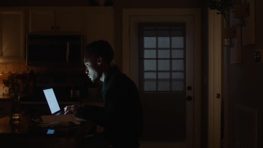 Man working on a laptop in the kitchen at night