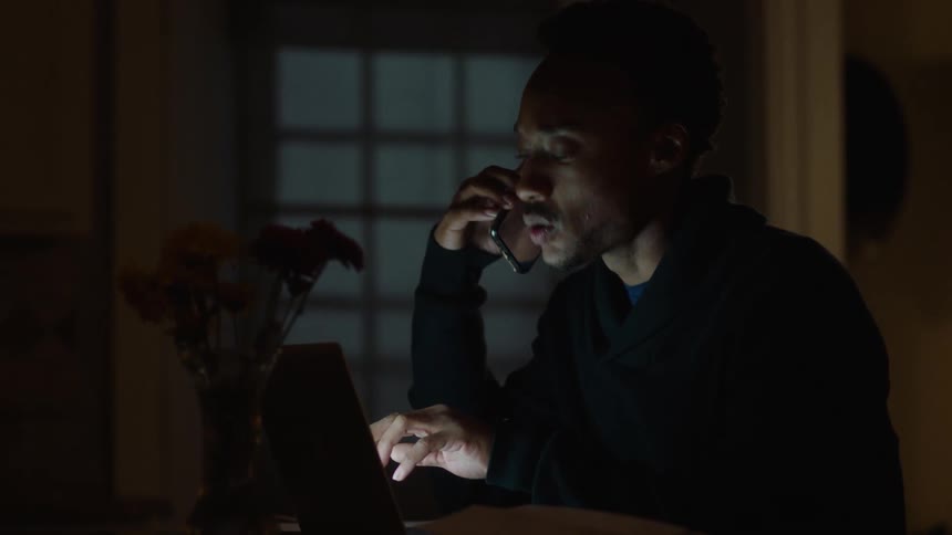 Man sitting talking on the phone with a laptop in front of him