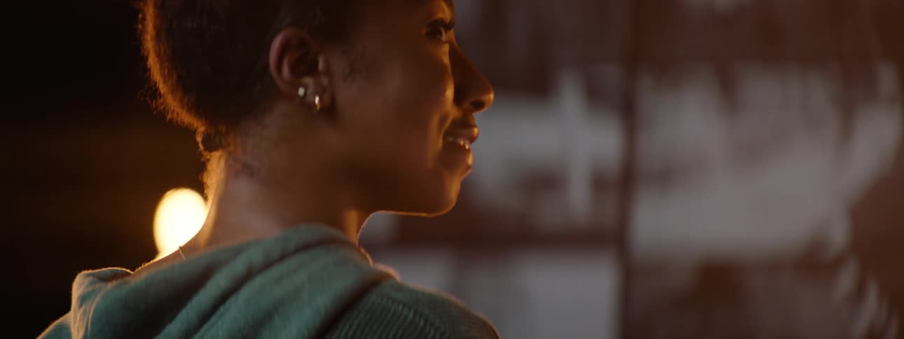 A young female smiling in front of a bright light at night