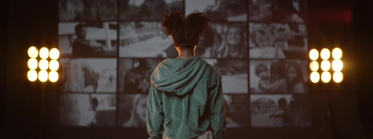 Child facing and with their back to a screen displaying memories of people in footage