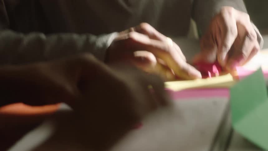 A father and daughter are doing origami inside