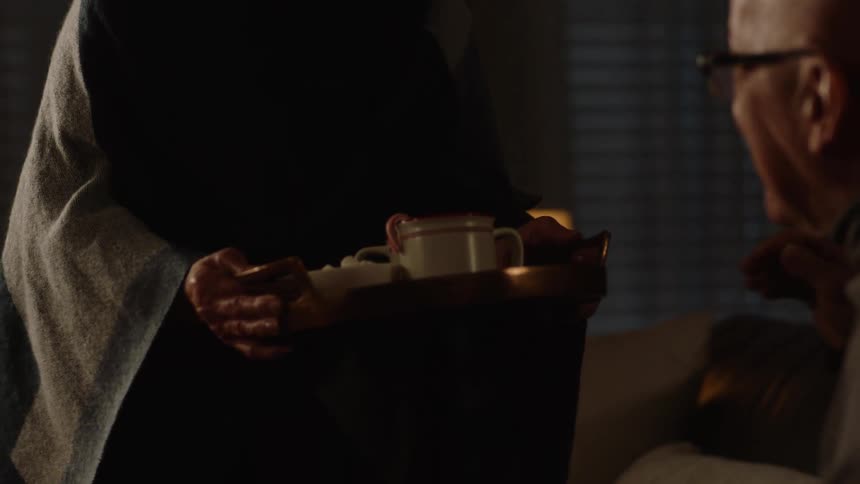 A woman offering tea on a tray to visitors
