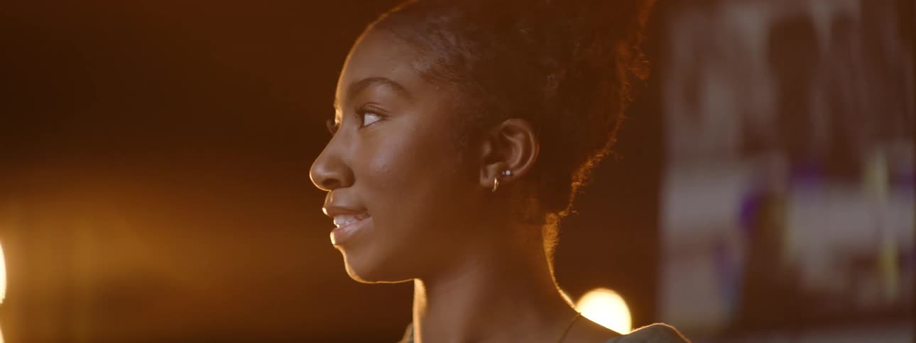 A young woman smiling and looks forward while her skin is illuminated by a light