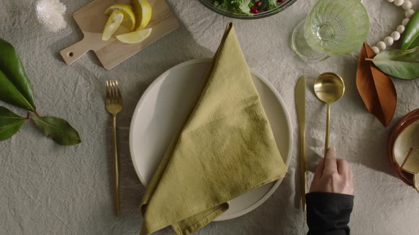 A person placing golden cutlery on a table