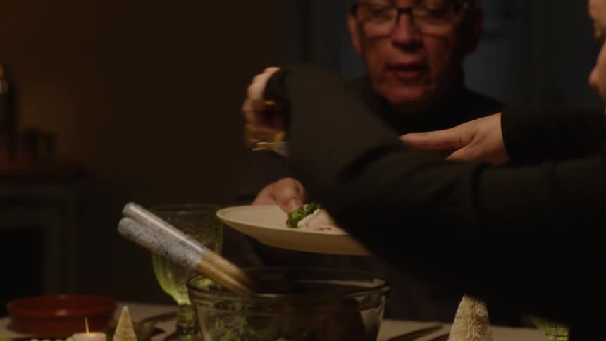 A woman serving food on a mans plate and they are both sitting