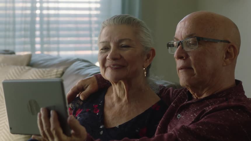 Parents sitting on a couch send regards on a video call