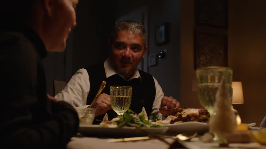 A family having dinner with a man laughing as they prepare to eat