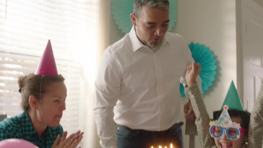 Parents and siblings celebrating the youngest sons birthday with a cake and candles