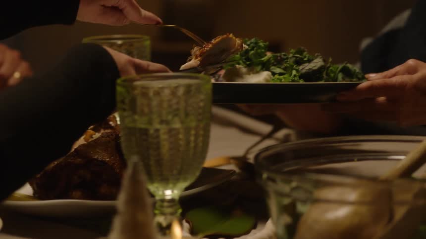 Hands of a person putting meat on an elderly womans plate