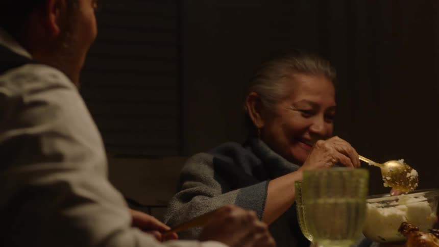 A family having dinner as the elderly woman serve herself