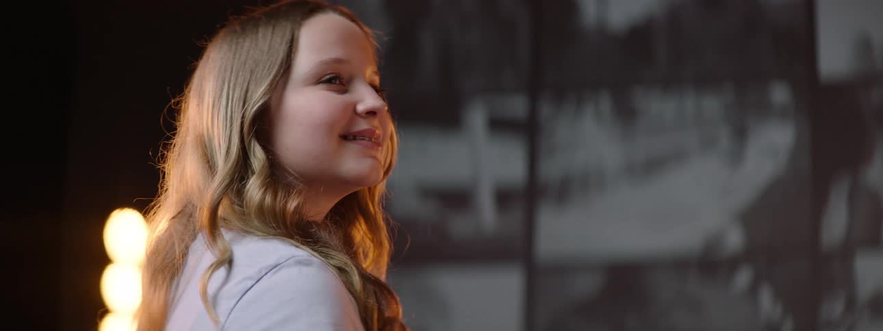 Young blonde woman looking at screens turn around smiling