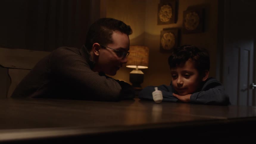 Brother spinning a spinning top on the table while his brother watches