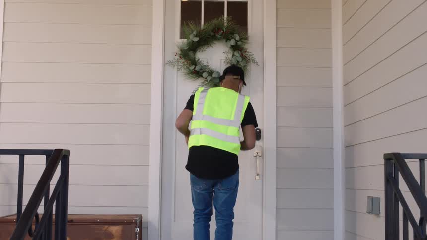A man knocks on the door of a house and leaves a package on the door and leaves