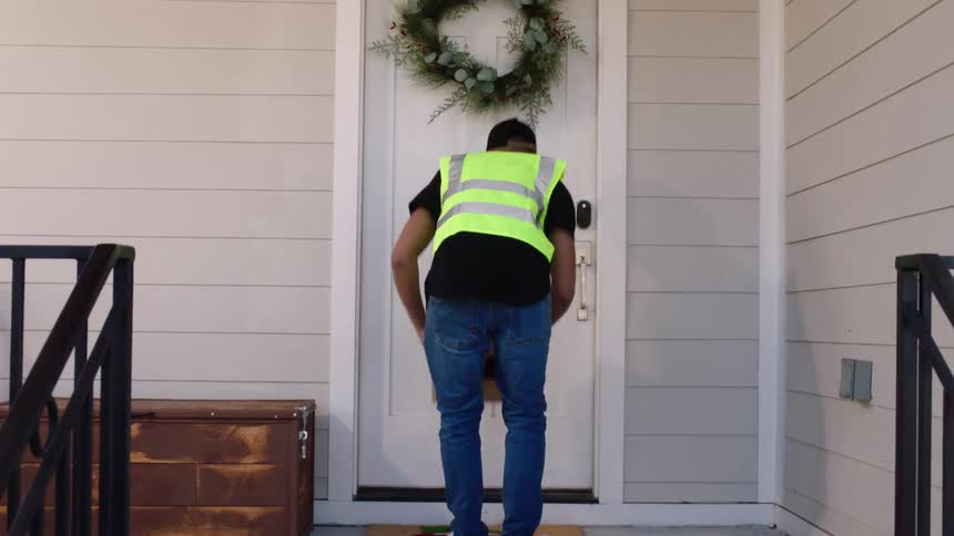 Delivery man places packages on doormat after knocking on door