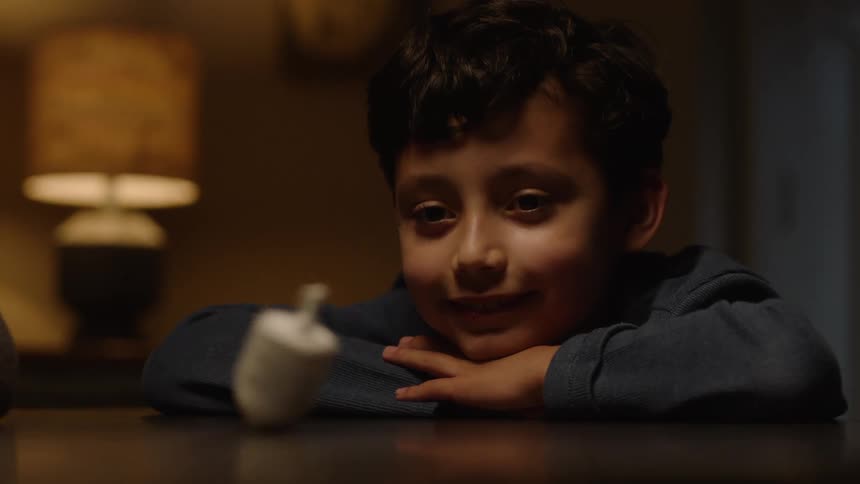A little boy watching a toy spin on the table