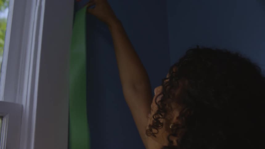 Happy woman tapes the windowsill before painting