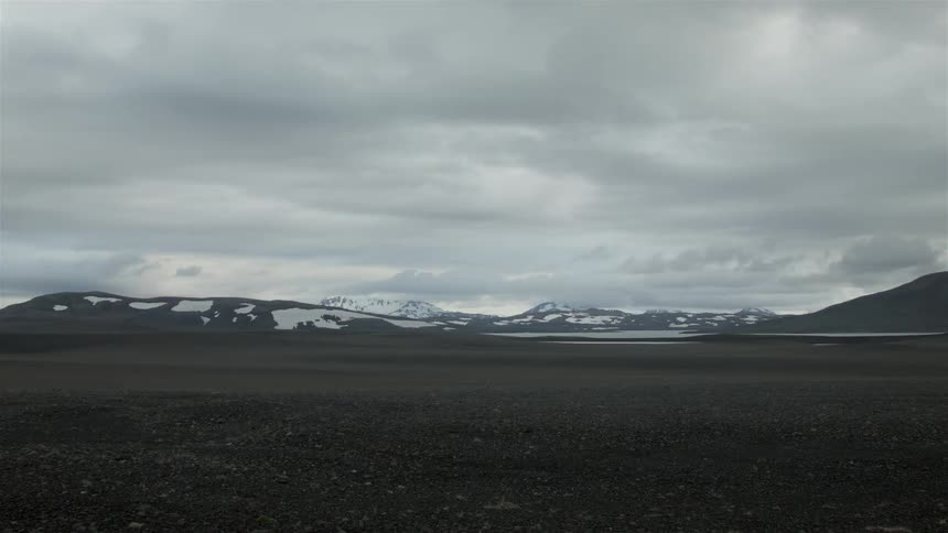 A field leads to snow covered mountains ahead
