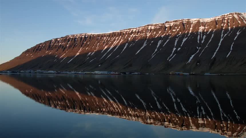 The water is calm near this mountain