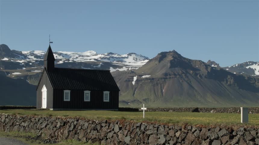 A church sits on a green field before a mountain