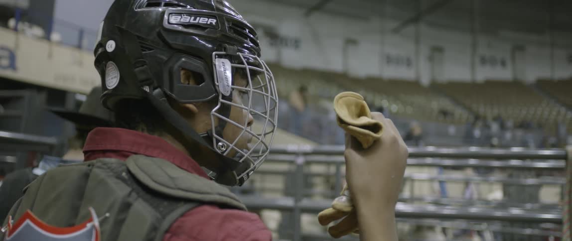Cowboy adjusting his helmet before a bull ride