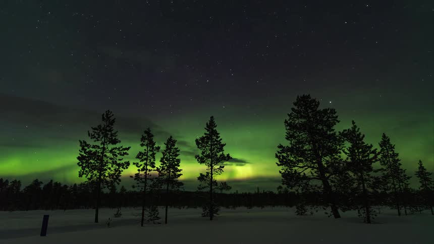 A snow covered field has green flares in the winter night